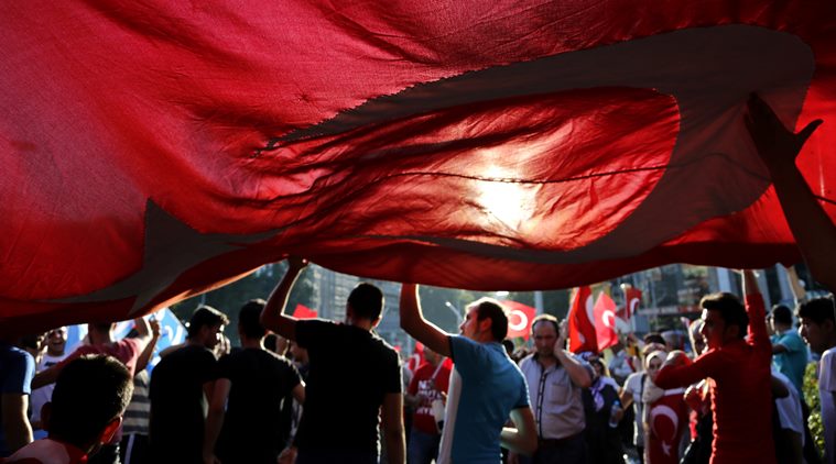 Turkish citizens wave a huge national flag as they protest against the military coup outside Turkey's parliament near the Turkish military headquarters in Ankara, Turkey, Saturday, July 16, 2016. Forces loyal to Turkey's President Recep Tayyip Erdogan quashed a coup attempt in a night of explosions, air battles and gunfire that left dozens dead Saturday. (AP Photo/Hussein Malla)